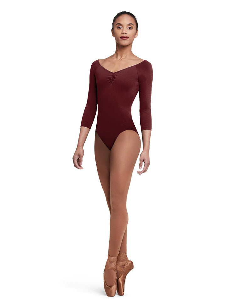 Dancer wearing a burgundy leotard and brown tights on a white background