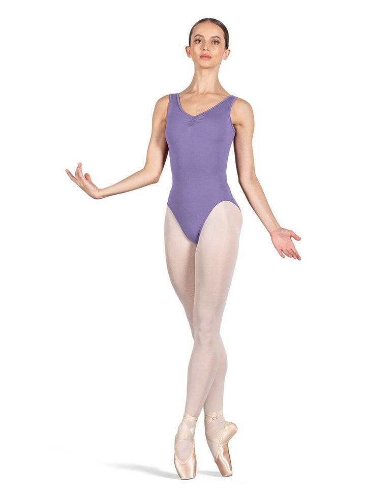 Ballerina in a purple leotard and beige tights on a white background