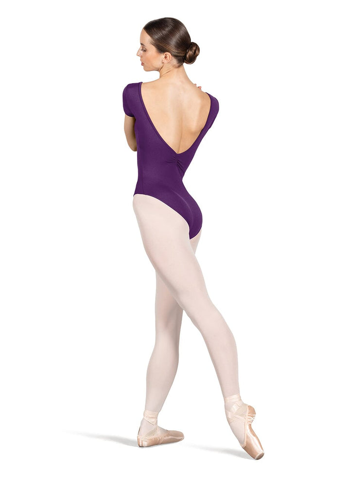 Ballerina in a purple leotard and beige tights on a white background