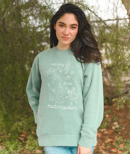 Person wearing a light green sweatshirt with text and graphics outdoors