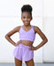 Young girl wearing a purple sports bra and shorts set against a white background