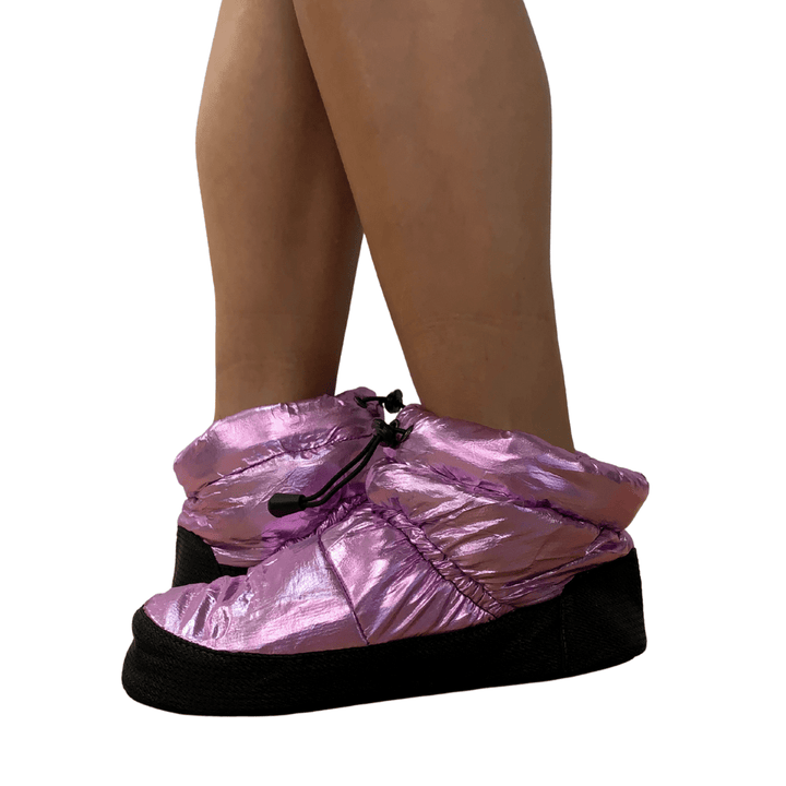 Pink metallic shoe covers being worn on a white background