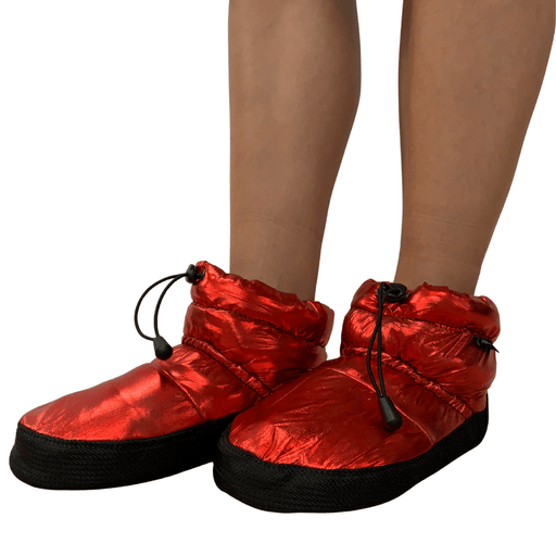 Red slip-on shoes with black soles worn by a person on a white background