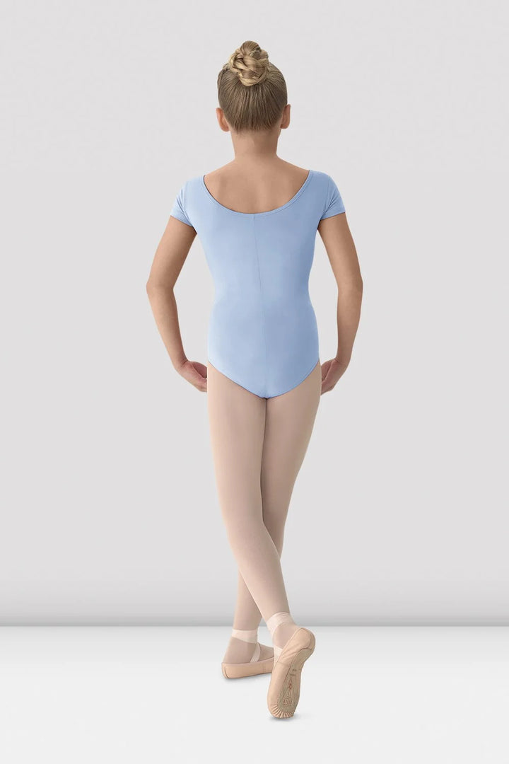 Ballerina in a blue leotard and beige tights standing on a white background