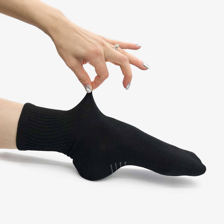 Black ankle sock being worn on a white background