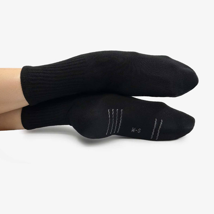 Black socks being worn on a white background