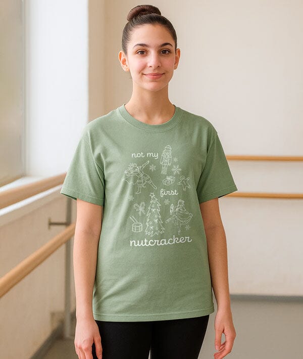 Person wearing a green t-shirt with a graphic design and text in a dance studio.