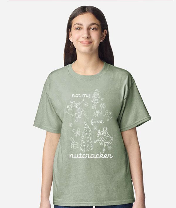 Person wearing a green t-shirt with 'not my first nutcracker' design on a white background