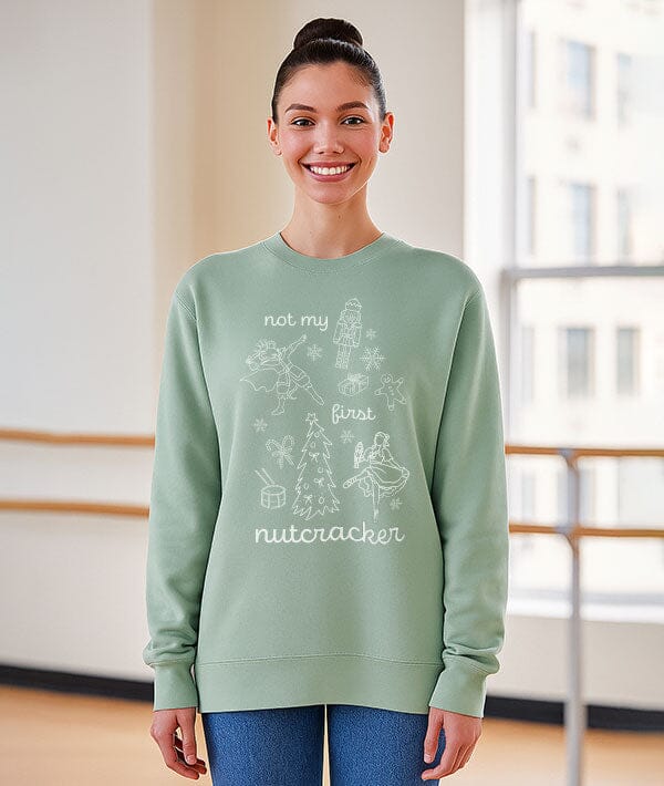 Woman wearing a light green sweatshirt with text and graphics, standing indoors.