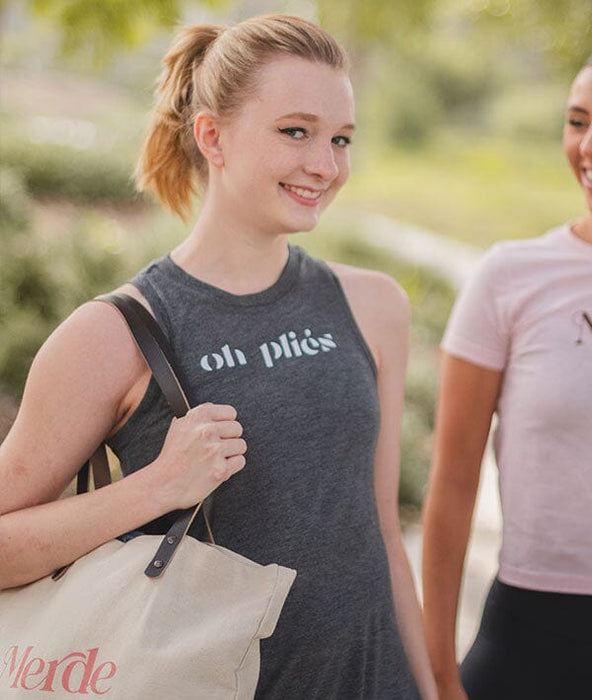 Two women walking outdoors, one wearing a tank top with 'oh plies' text.