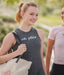 Two women walking outdoors, one wearing a tank top with 'oh plies' text.