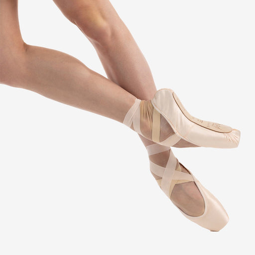 Ballet shoes with straps worn by a dancer on a white background