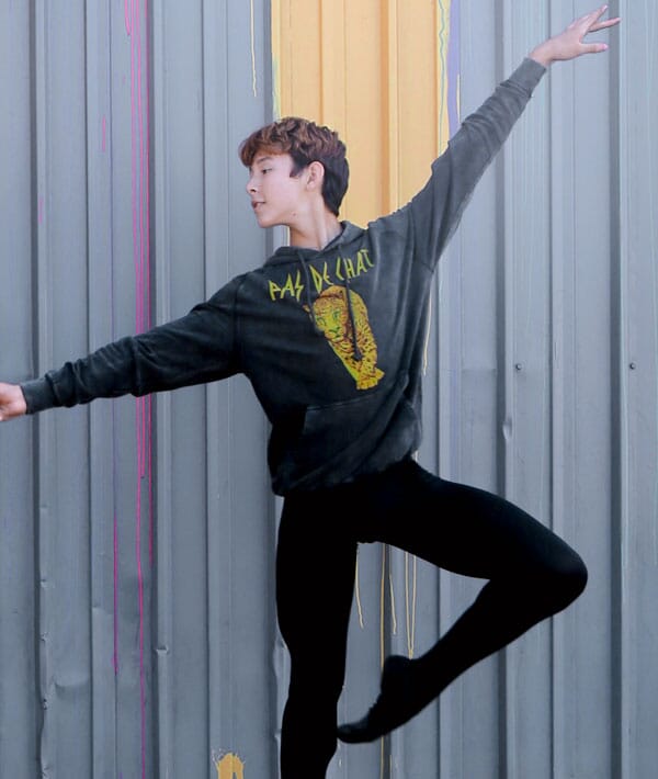 Male dancer in a hoodie in front of a metal building