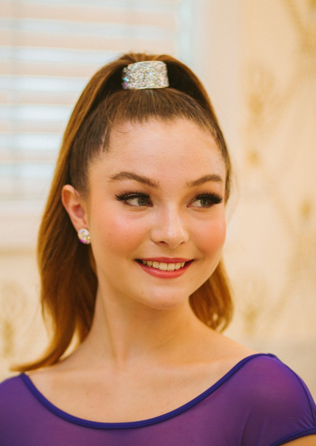 Woman with a high ponytail wearing a decorative hair clip against a neutral background