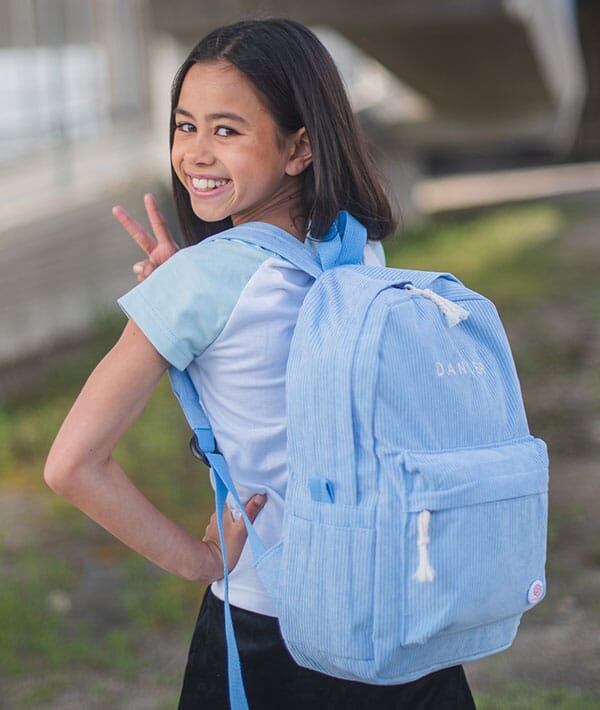 Girl wearing a light blue backpack outdoors