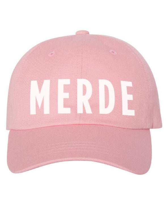 Pink cap with 'MERDE' printed on it against a white background