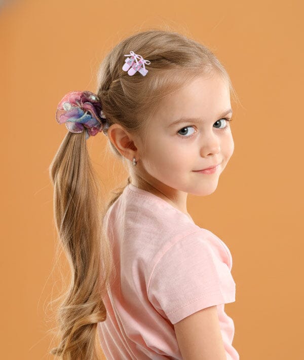 Young girl with a ponytail and decorative hair clip against an orange background
