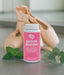 Pink bottle of pointe powder with ballet shoes and eucalyptus leaves on a neutral background