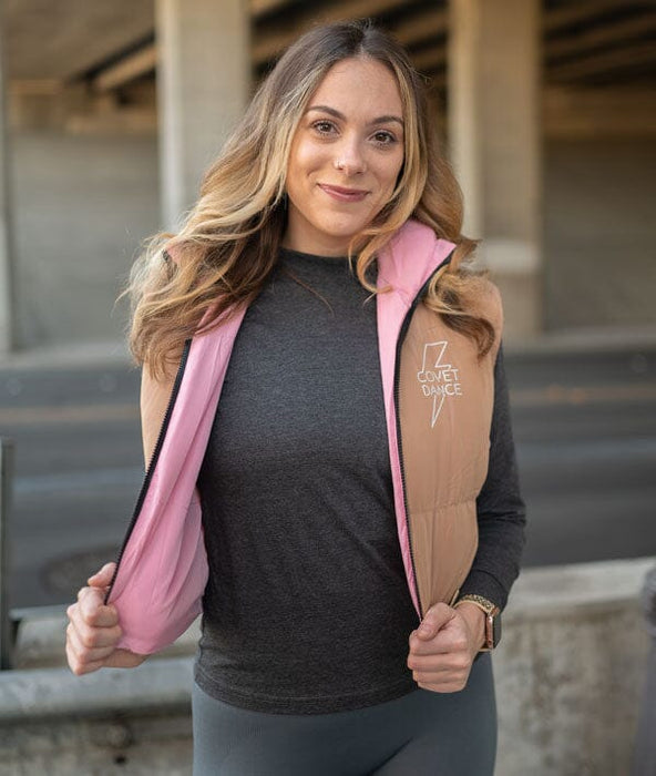 Woman wearing a brown and pink jacket with a visible brand logo, standing outdoors.