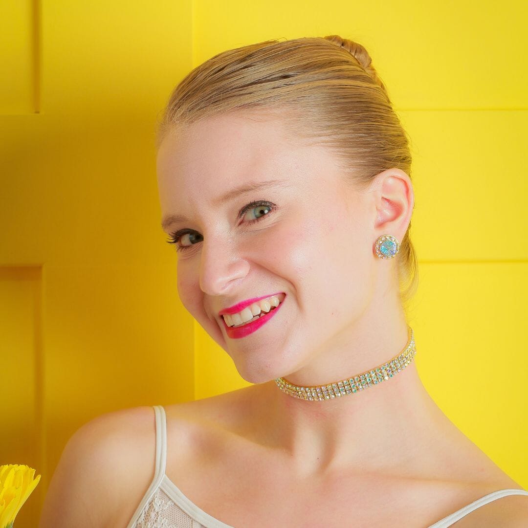 Woman wearing a diamond necklace and earrings against a yellow background