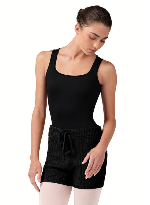 Woman wearing a black tank top and shorts on a white background