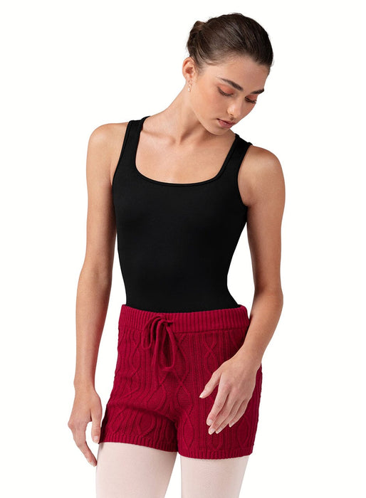 Woman wearing a black tank top and red shorts on a white background