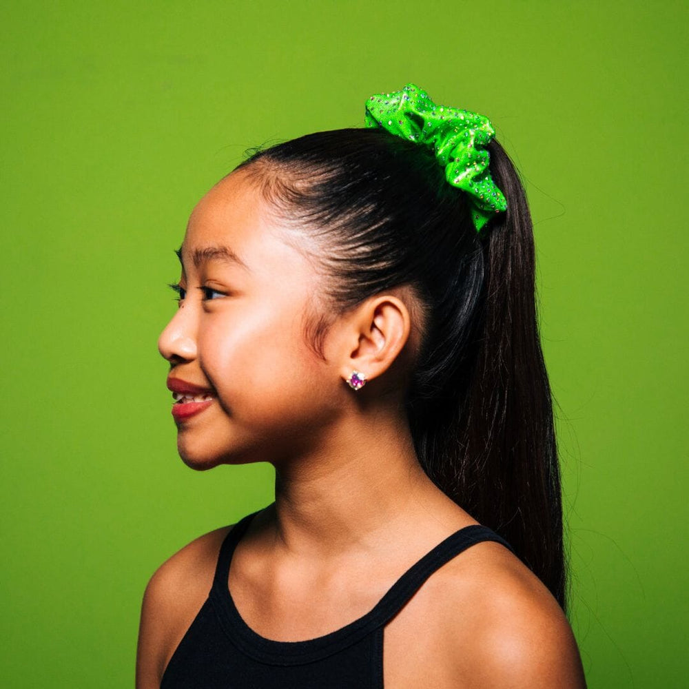 Young girl with a green hair accessory against a green background