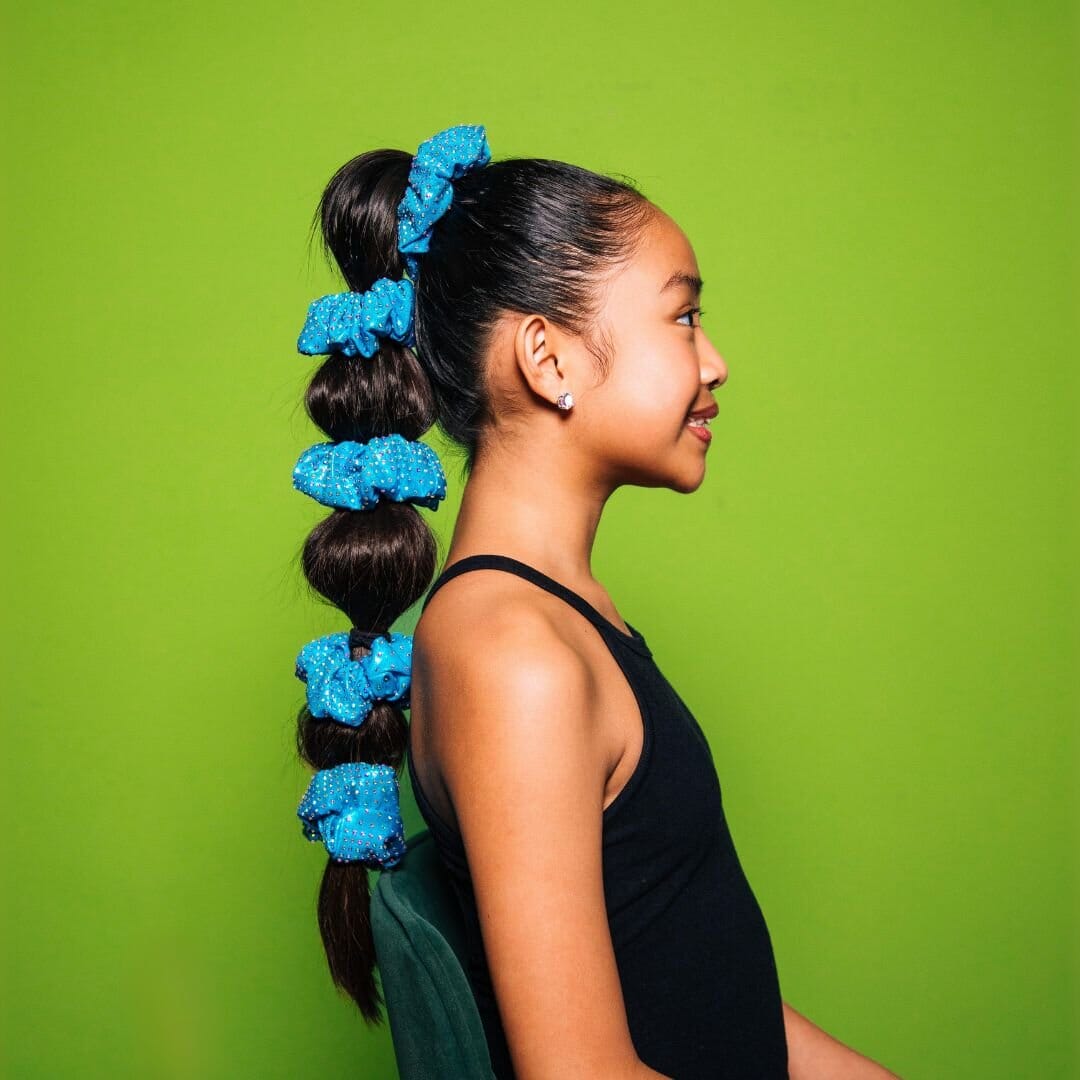 Woman with blue scrunchies in her hair against a green background