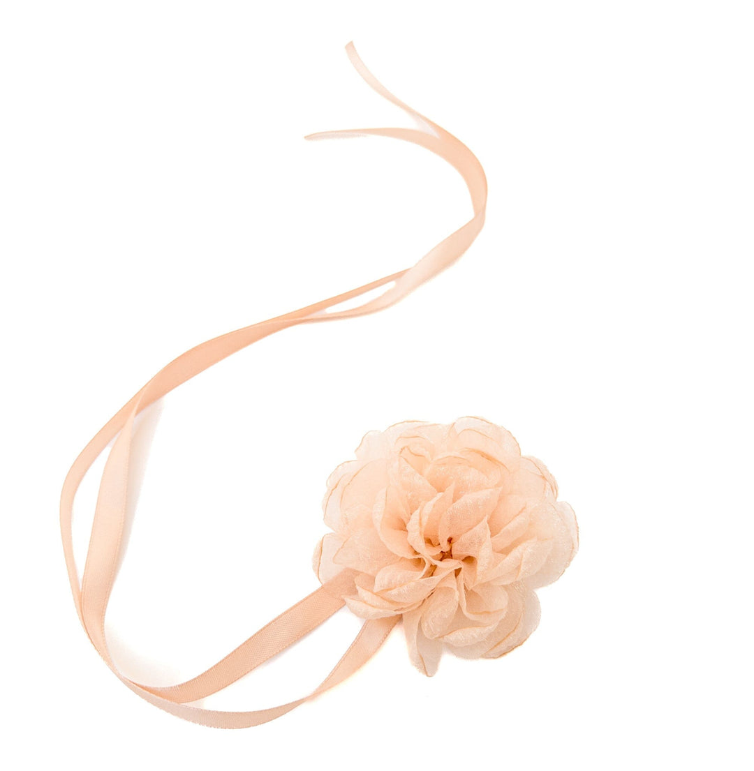 Peach-colored headband with a flower accessory on a white background