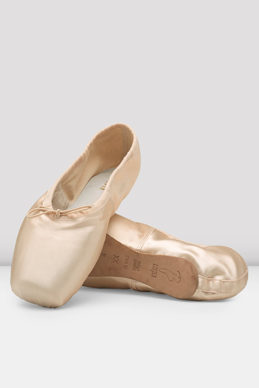 Pair of beige ballet shoes on a light gray background