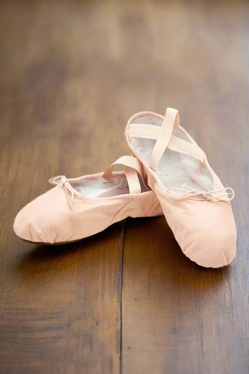 Pair of pink ballet shoes on a wooden dance floor