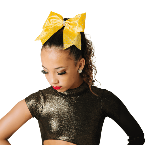 Young girl wearing a black sequin top with a yellow bow in her hair on a white background