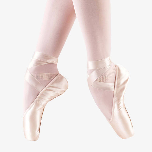 Ballet shoes worn with pink tights on a white background