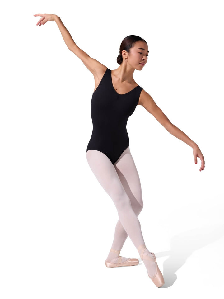 Ballerina in a black leotard and white tights posing on a white background