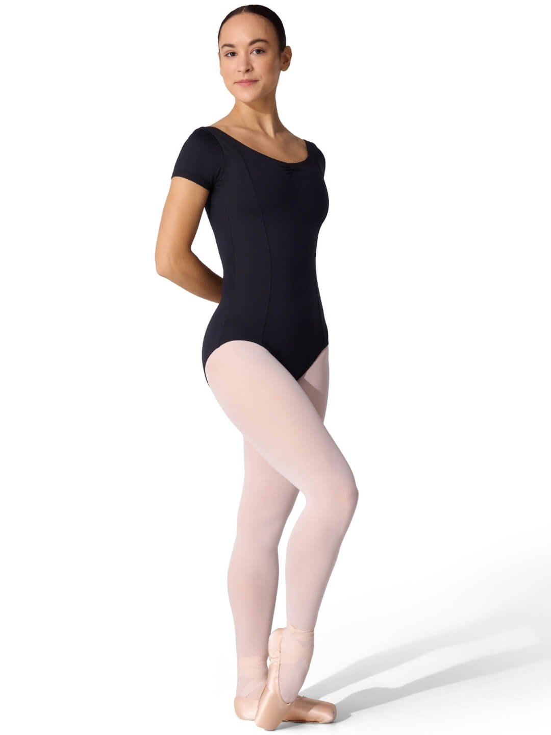 Person wearing a black leotard and beige tights on a white background