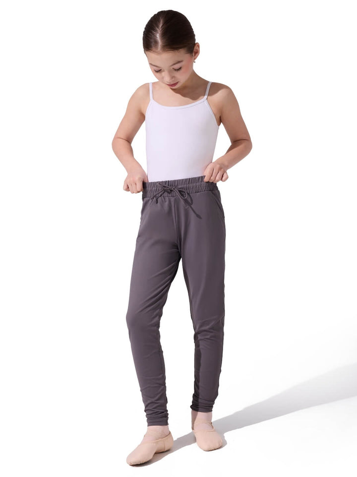 Young girl wearing gray dance pants and a white top on a white background