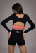 Person wearing a black long-sleeve crop top and black shorts with pink waistband on a gray background