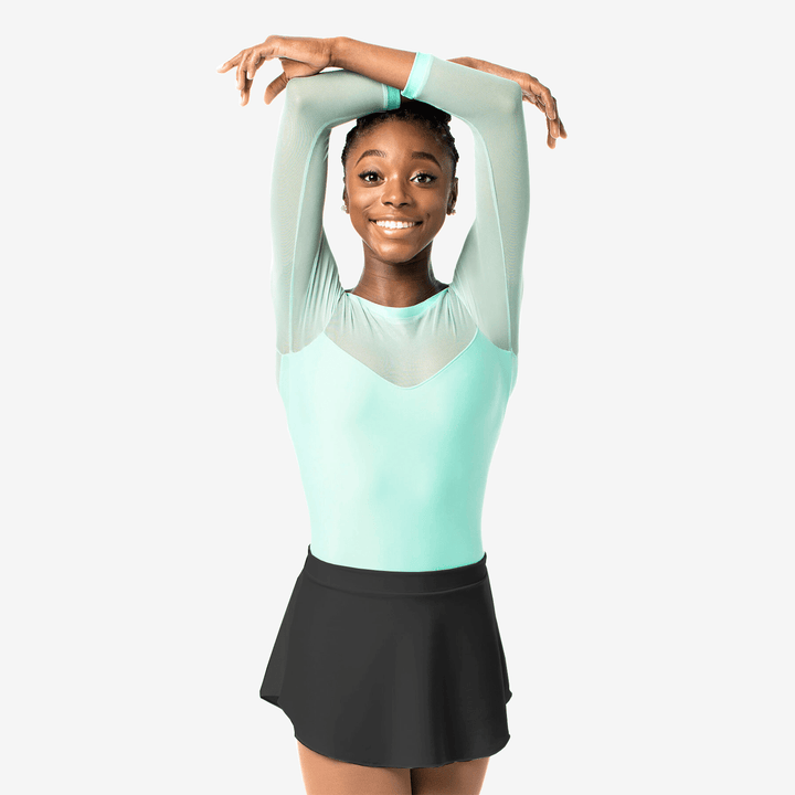 Young girl in a light blue top and black skirt posing against a white background