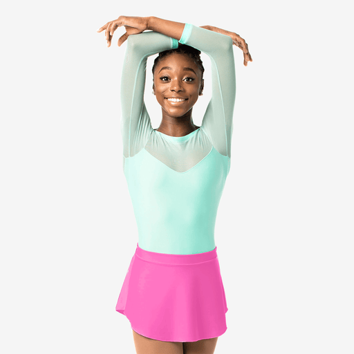 Young girl in a light blue top and pink skirt posing against a white background