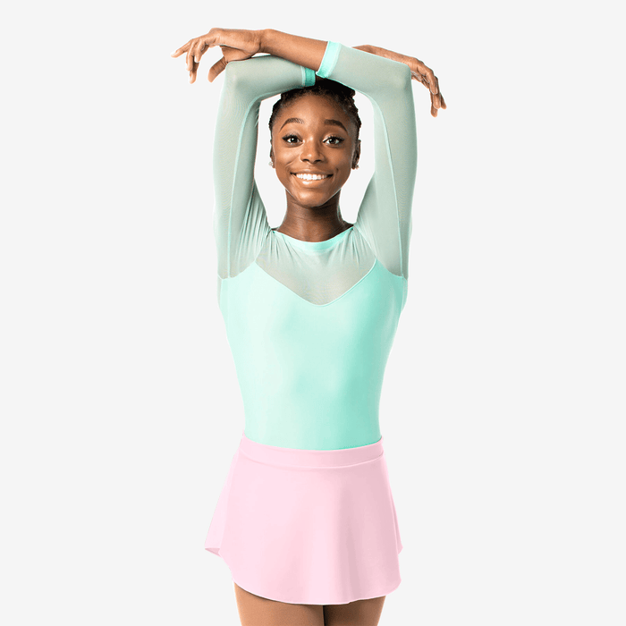 Young girl in a light green top and pink skirt posing against a white background