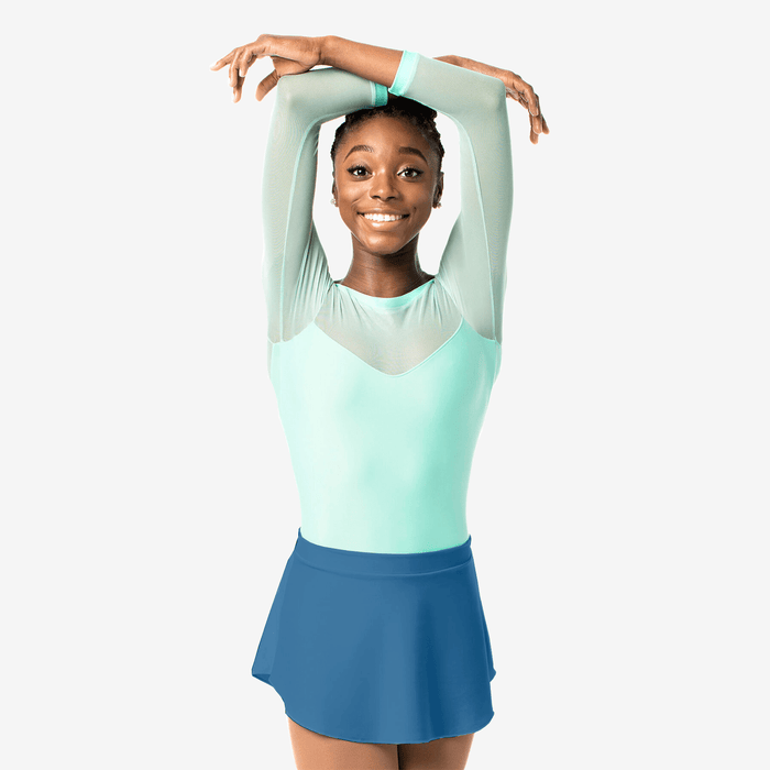 Young girl in a light green top and blue skirt posing against a white background