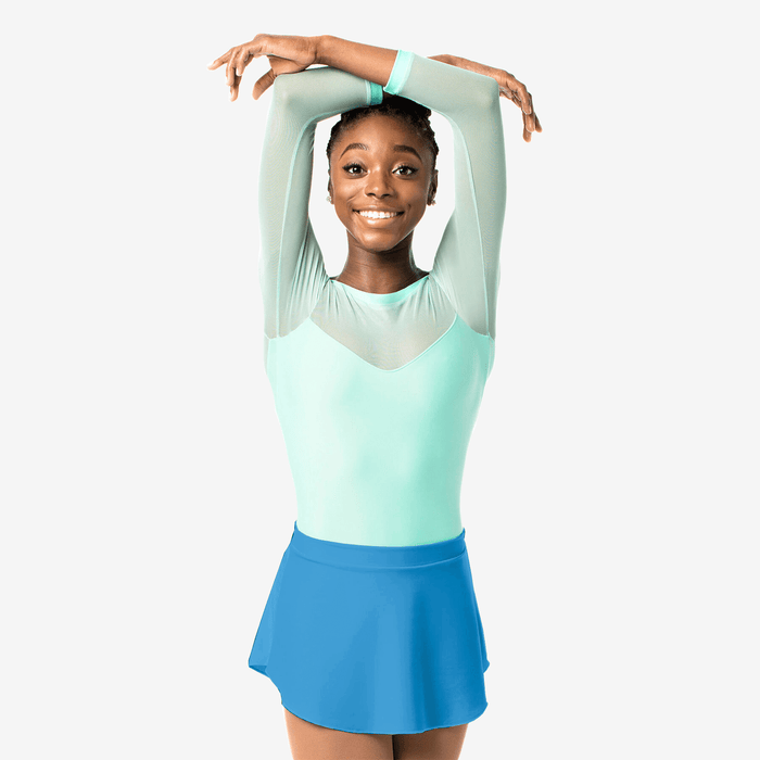 Young girl in a light green top and blue skirt posing against a white background
