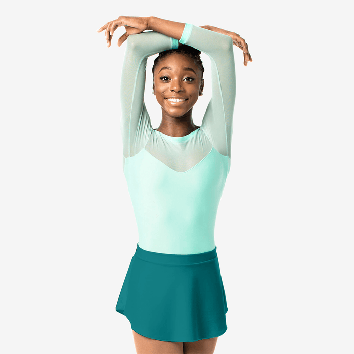 Young girl in a light green top and teal skirt posing against a white background