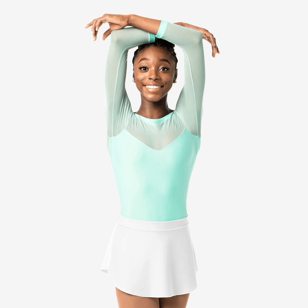 Woman in a light green and white outfit posing against a white background