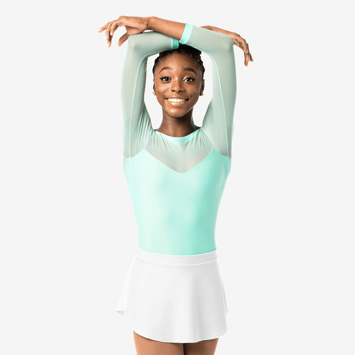 Woman in a light green and white outfit posing against a white background