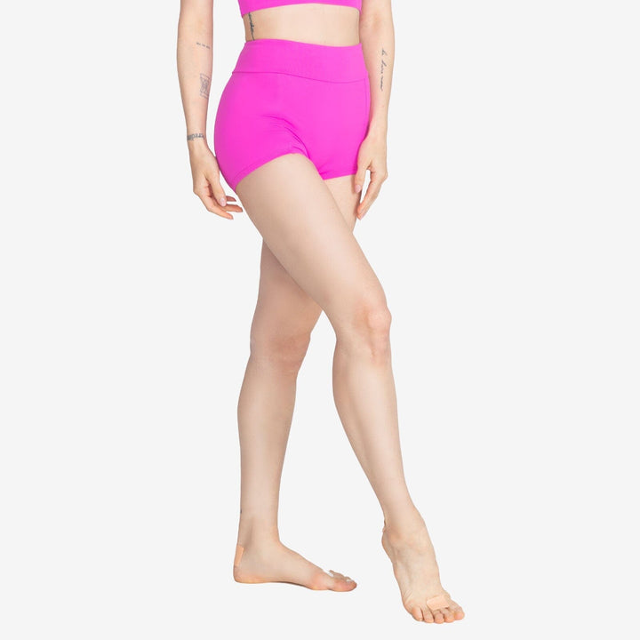 Person wearing bright pink high-waisted shorts on a white background
