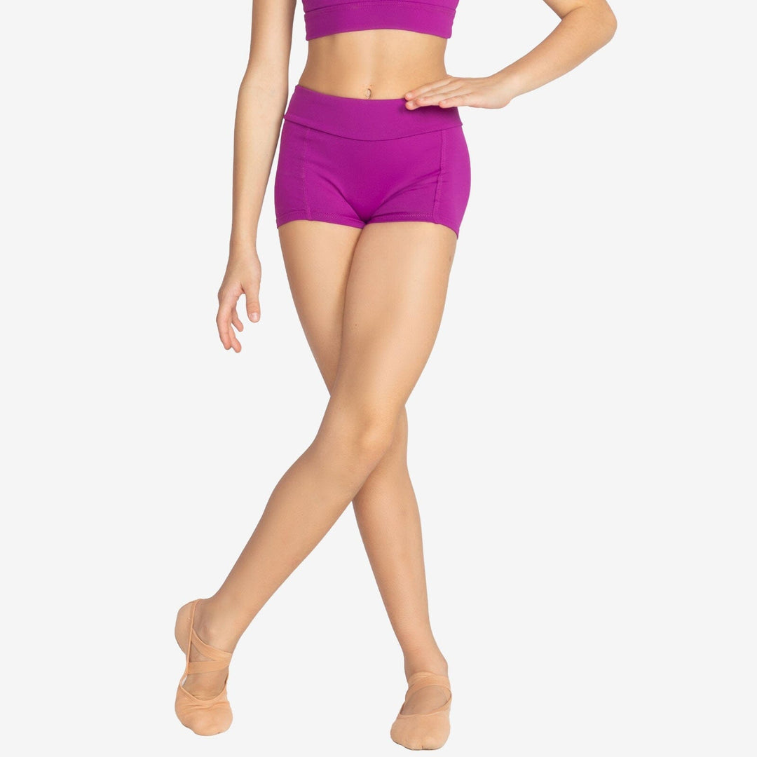 Person wearing purple athletic shorts and beige ballet flats on a white background