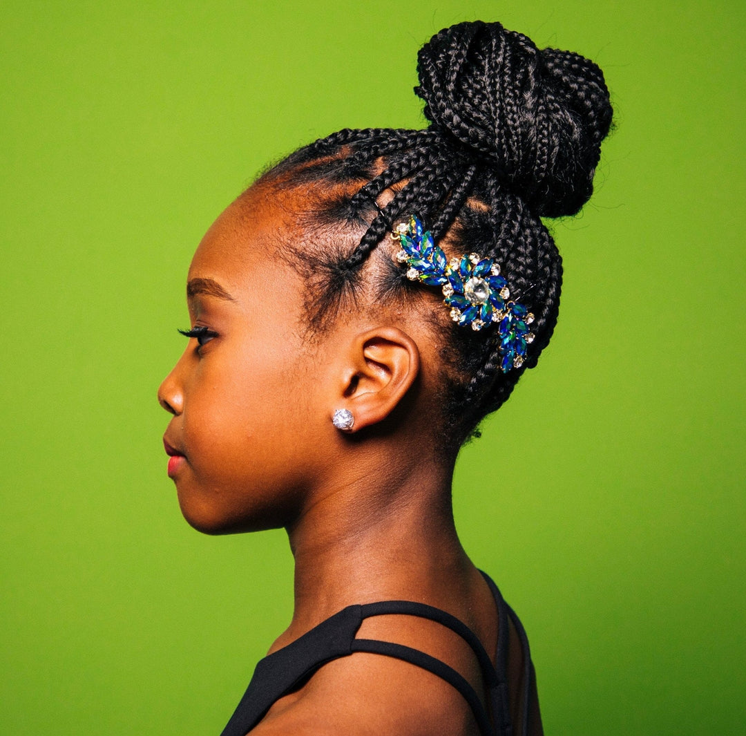Profile of a person with braided hair and decorative hairpiece against a green background
