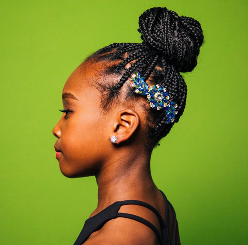 Profile of a person with braided hair and decorative hairpiece against a green background