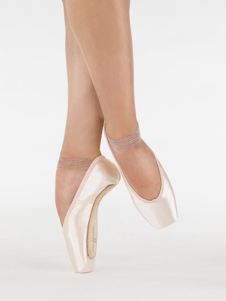 Ballet shoes worn with sheer tights on a white background
